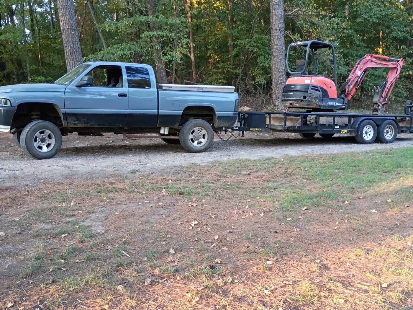 Red Dirt truck hauling a mini excavator for local dirt work