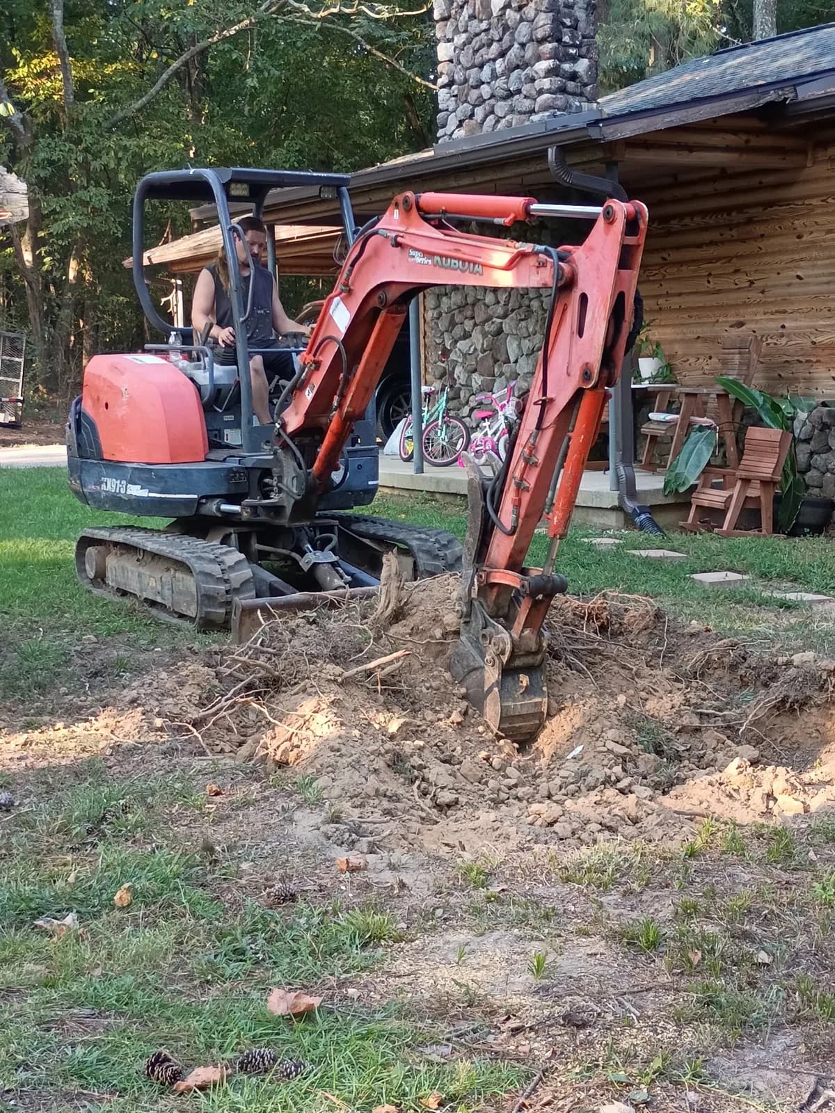 Mini excavator working around stump roots during property cleanup